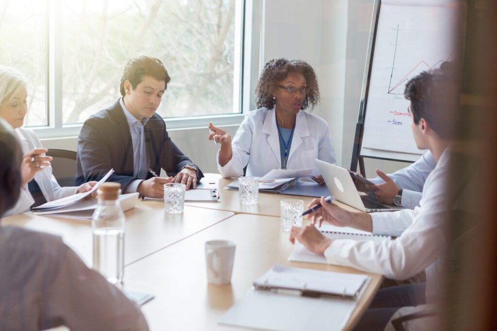 Mature female doctor participates in meeting with hospital administration. She gestures while talking about a serious issue.