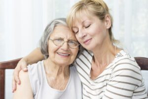 Beautiful mature daughter with closed eyes hugging her senior mother.